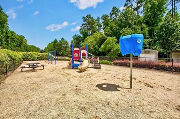 a playground with a playground equipment and picnic table in a park